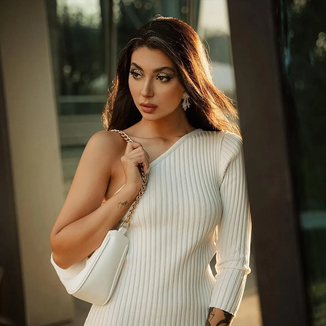 Woman in a cream knit dress with bronzed evening glam and voluminous curls